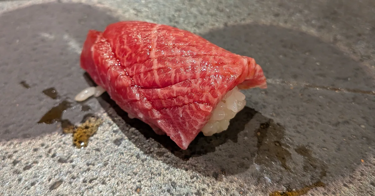 Fatty tuna nigiri served on a ceramic plate at a sushi counter
