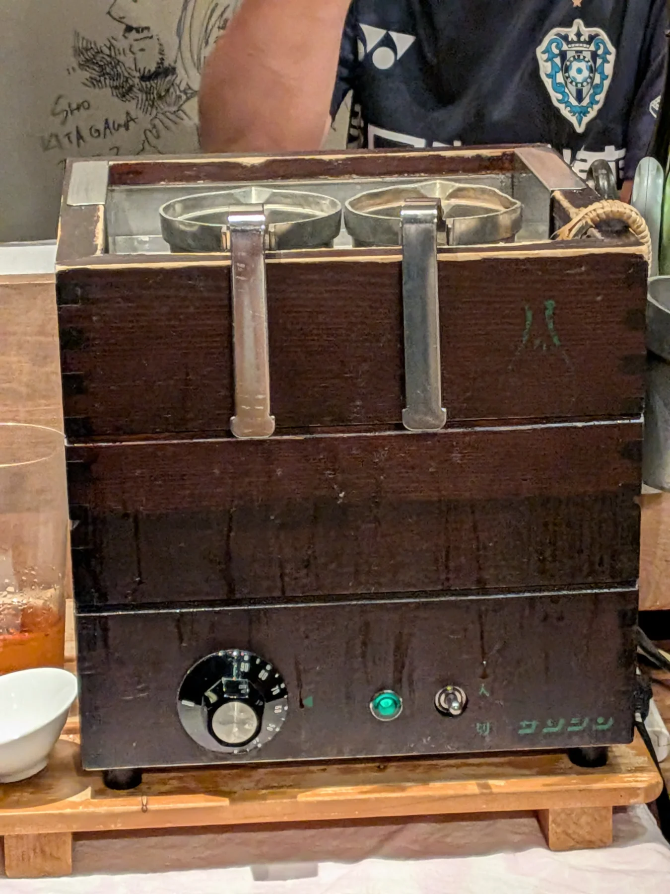 Sake-warming device in use at Enrai, staff member's arm visible