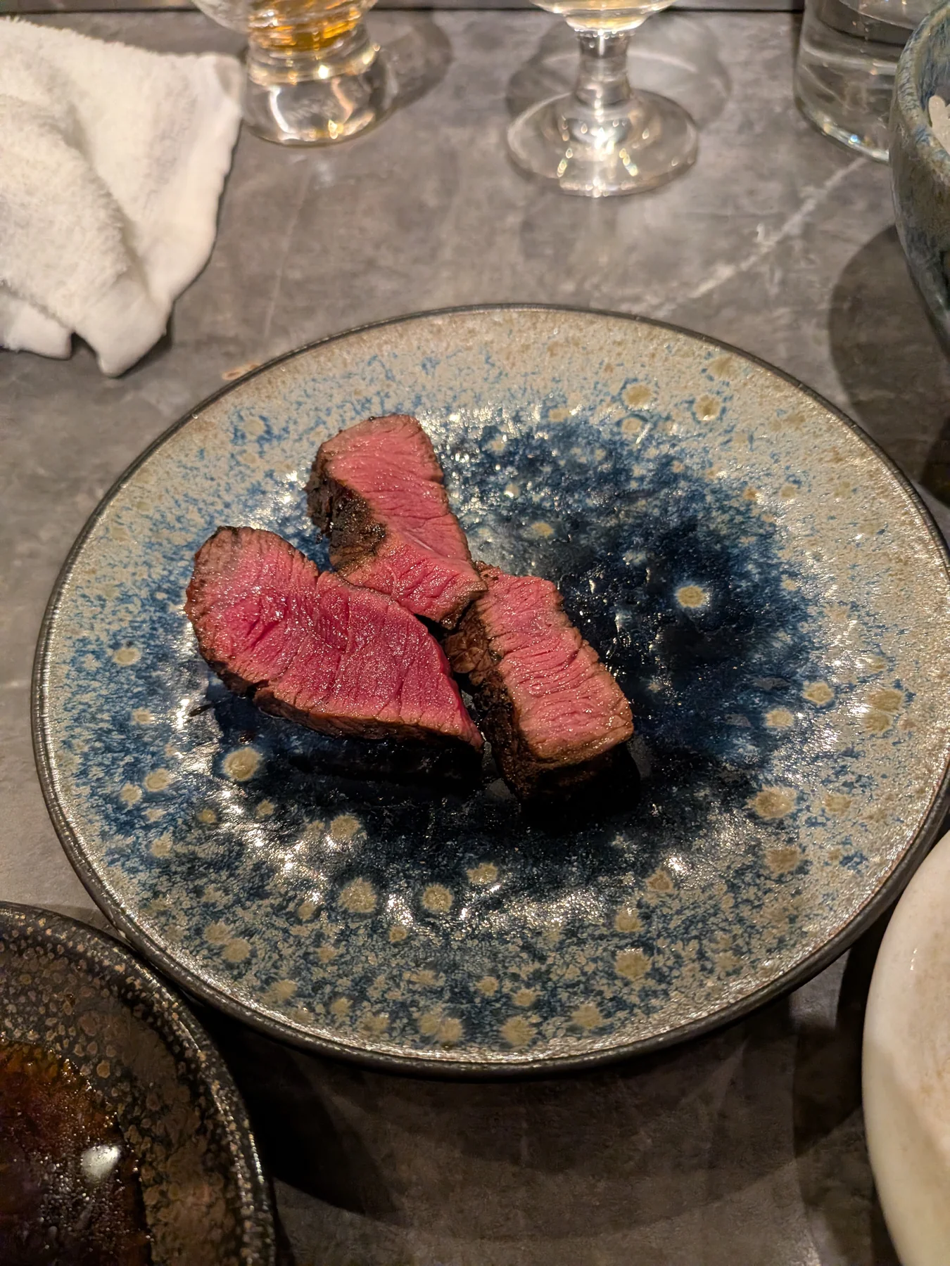 Plated aged beef tongue with sake glass at Nose to Tail
